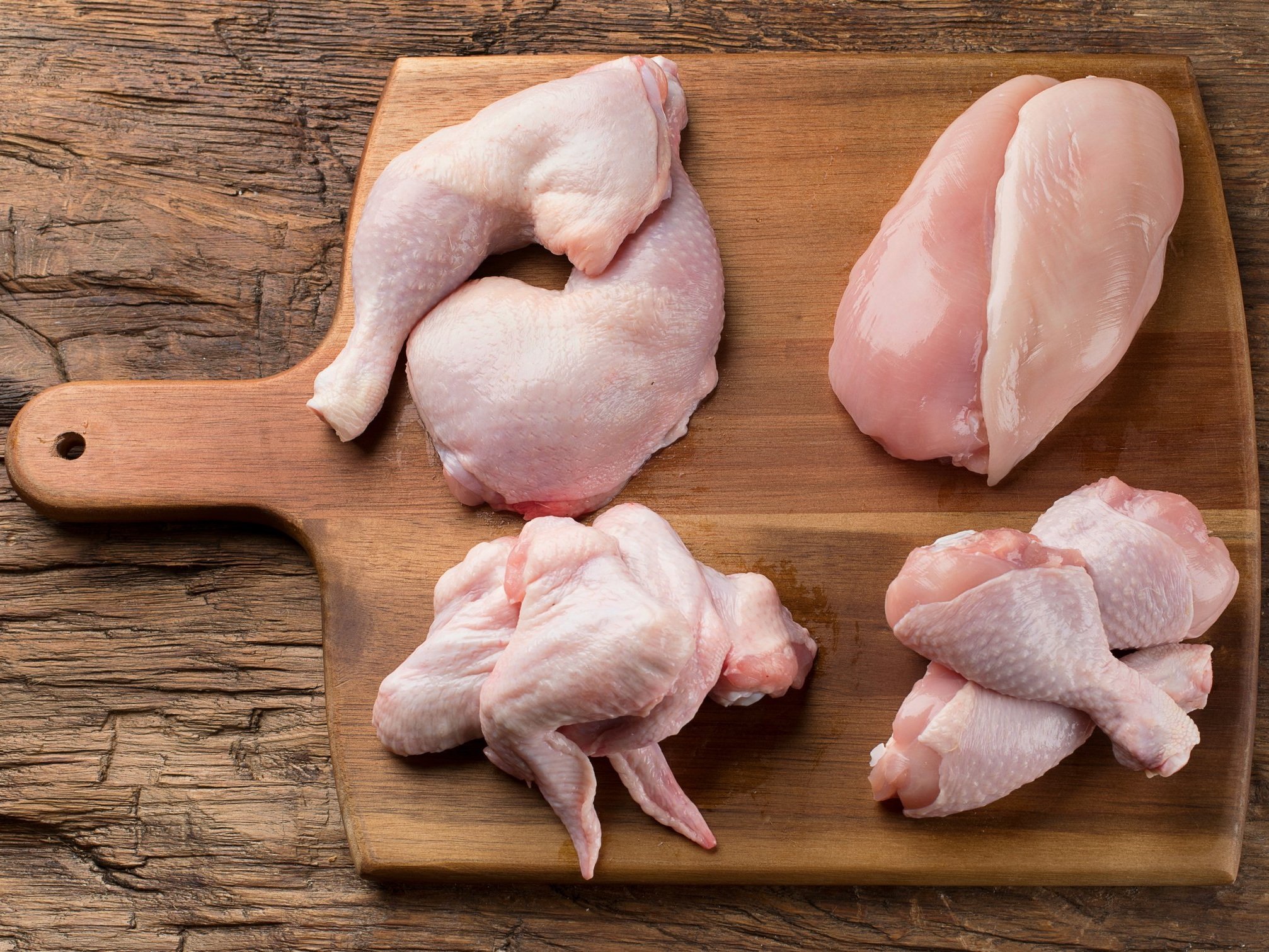 chicken_cuts_variety_woodcuttingboard (5) Raw chicken pieces including thighs, drumsticks, and breast displayed on a wooden cutting board, showcasing fresh poultry for cooking.